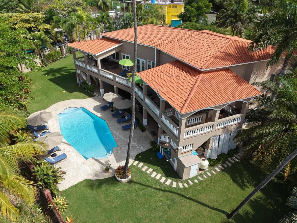 Aerial view of the red-roofed villa and pool directly on the shoreline of Maria's Beach